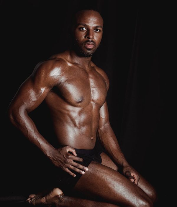 Strong man performing rhythmic power exercises in a dark studio.